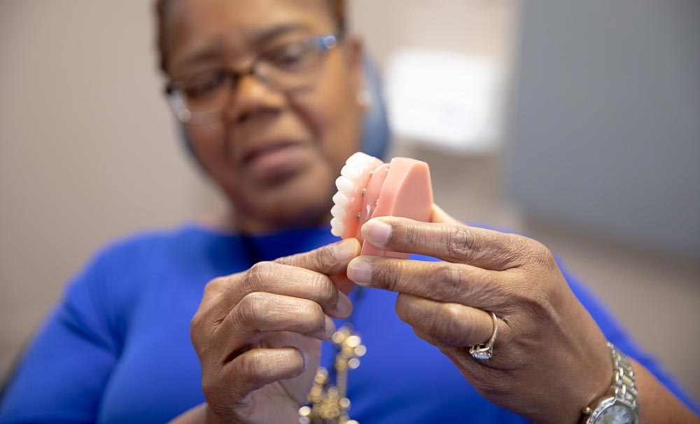 a patient holding a model of dentures